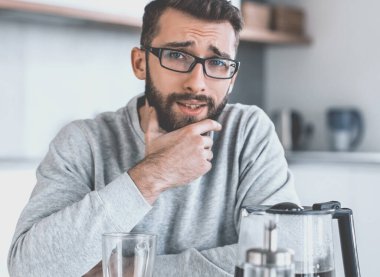 çekici bir adam sabahleyin mutfak masasında oturuyor.