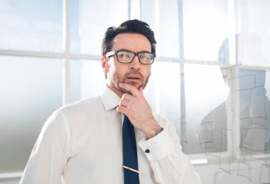 Ciddi düşünceli iş adamı ofiste dikiliyor.