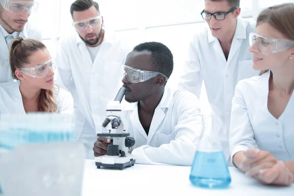 Químicos focados e sérios do sexo feminino e masculino em casacos de laboratório e óculos de segurança fazendo experiências — Fotografia de Stock