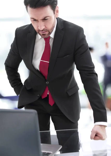 Affärsman står vid sitt skrivbord och tittar på den bärbara skärmen — Stockfoto