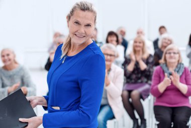 Orta yaşlı yönetici kadın kameraya bakıyor.