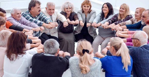 Un grupo de personas maduras extendió sus brazos hacia adelante sentarse — Foto de Stock