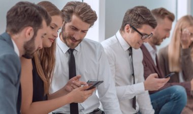 Şirketin genç çalışanları akıllı telefonlarının ekranlarına bakıyor.