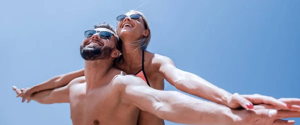 Uomo che trasporta donna a cavalluccio sulla spiaggia. — Foto Stock