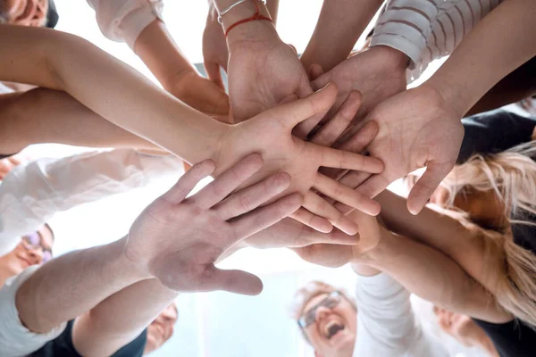 Ansicht von unten. Ein Team junger Leute bastelt einen Turm aus ihren Händen. — Stockfoto