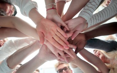 Alt manzara. Bir grup genç avuçlarını birleştiriyor.