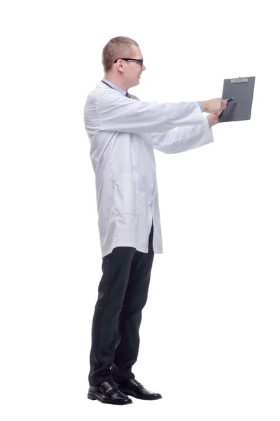 Young male doctor pointing and looking at the camera with a clipboart in his hand and a smile on his face — Stock Photo, Image