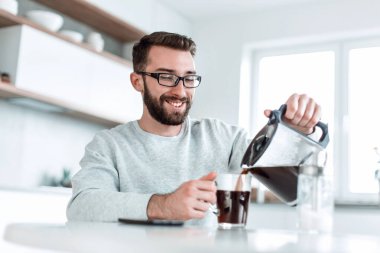 Çekici adam kendine bir fincan sabah kahvesi dolduruyor.