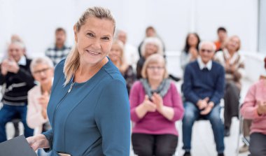Orta yaşlı yönetici kadın kameraya bakıyor.