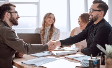 Ofisteki bir toplantıda tokalaşan iş adamları.