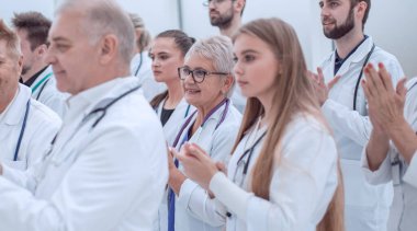 Bir grup tıbbi pratisyen birlikte alkışlıyor..