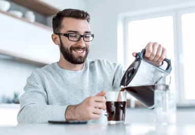 Çekici adam kendine bir fincan sabah kahvesi dolduruyor.