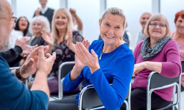 Bir grup yaşlı insan bir çemberin içinde oturmuş alkışlıyorlar.
