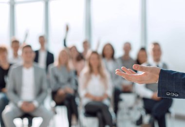 Kapat. Konuşmacı konferans odasında seyircilerin önünde duruyor.