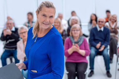 Orta yaşlı yönetici kadın kameraya bakıyor.