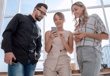 İş ekibi akıllı telefonlarının ekranlarına bakıyor.