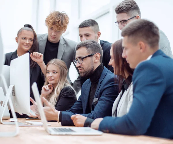 team of young employees looking together at a computer screen.