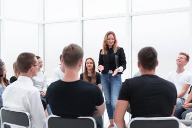 Genç bir kadın bir grup gençle iş eğitimi yapıyor..