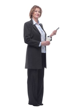 Kıdemli gülümseyen bayan elinde akıllı telefon ve bir fincan kahveyle ayakta duruyor.