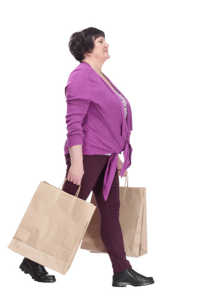 casual elderly woman with shopping bags striding forward.