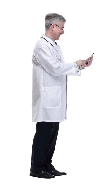 Médico sonriente con teléfono inteligente mirando hacia adelante. aislado en un blanco — Foto de Stock