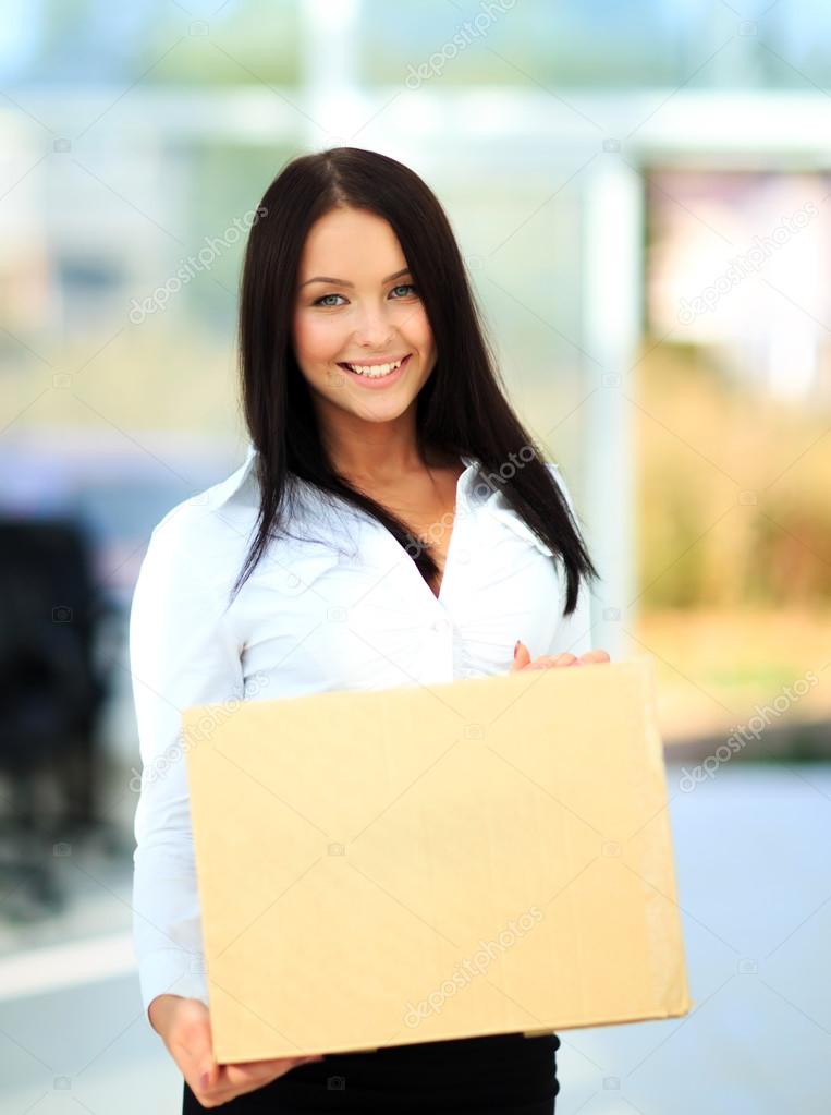 Closeup portrait of pretty adult woman holding a box at office building