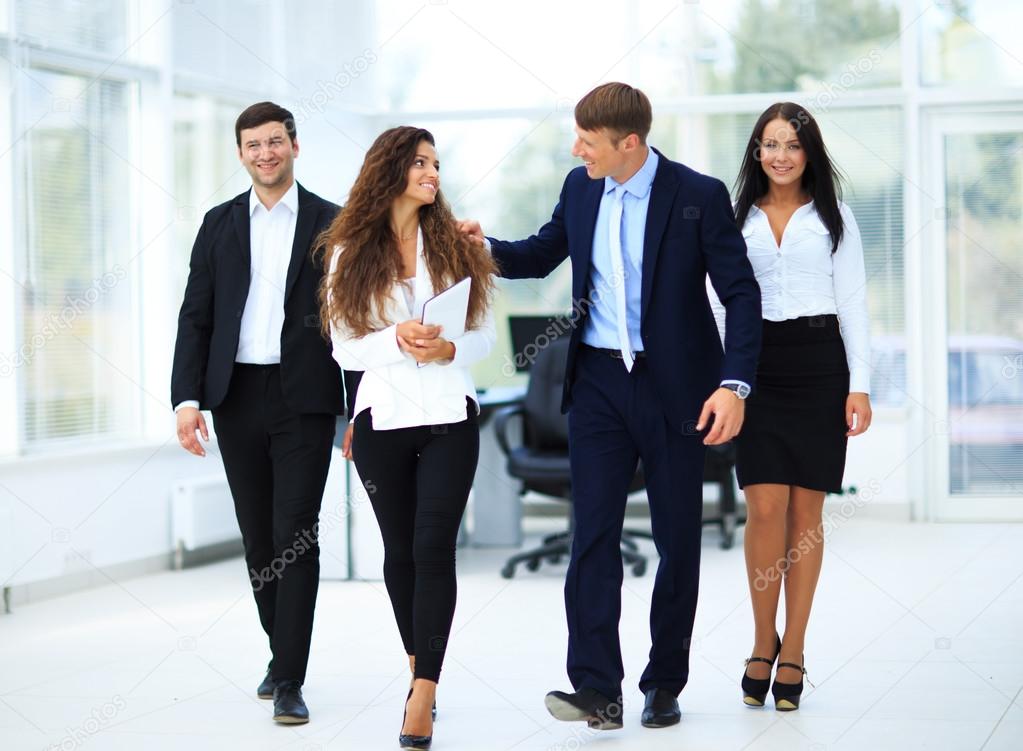 Confident business partners walking down in office building and