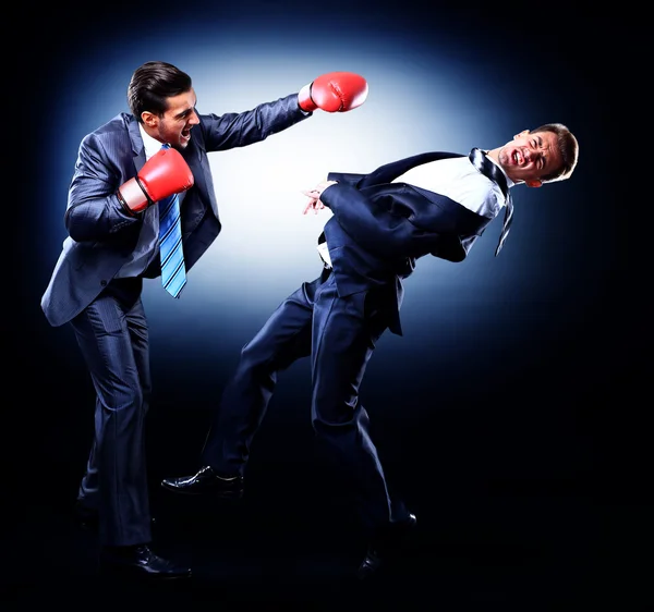 Dos jóvenes empresarios boxeando contra fondo oscuro — Foto de Stock