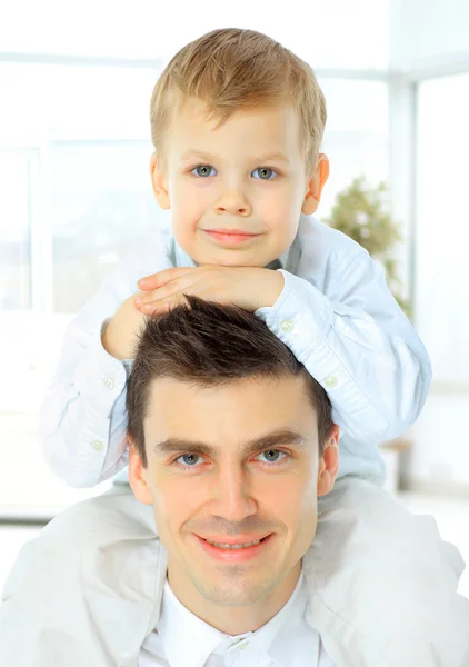 Portrait of the father  holding his son on his shoulders. both look at the camera and smiling — Stock Photo, Image