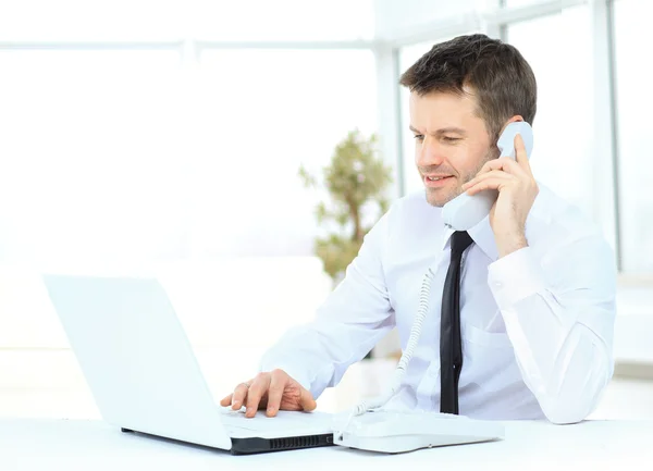 Homem de negócios trabalhando no computador e falando ao telefone — Fotografia de Stock