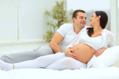 adam beyaz yatakta yatıyordu onun hamile eşi sevgiyle bakar