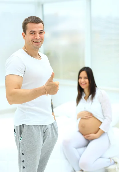 Man toont dat alles is goed op de achtergrond van zijn zwangere vrouw zitten — Stockfoto