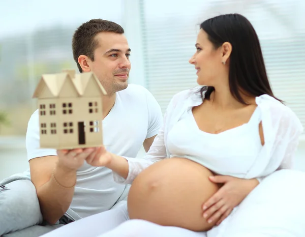 Man demonstrates his pregnant wife the model of the future home — Stock Photo, Image