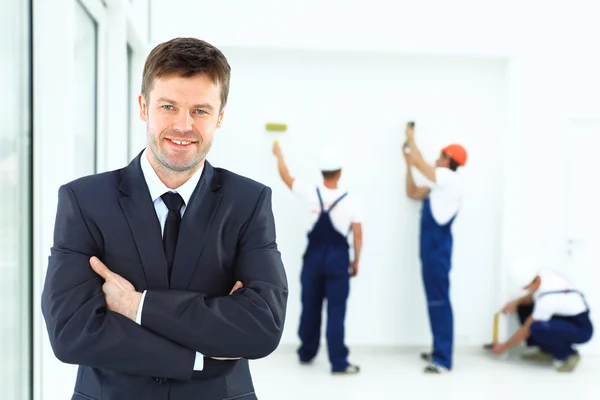 Porträtt av en leende ägare. mot bakgrund av ett team av byggare — Stockfoto