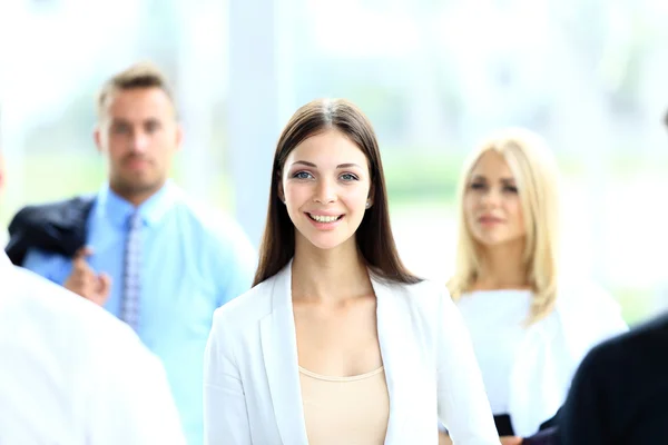 Успешная деловая женщина, стоящая со своим персоналом на заднем плане в офисе — стоковое фото