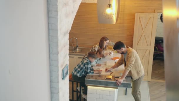 Αργή κίνηση στοργικών γονιών και έξυπνων παιδιών που κάνουν μαζί την εργασία τους στην κουζίνα στο σπίτι — Αρχείο Βίντεο