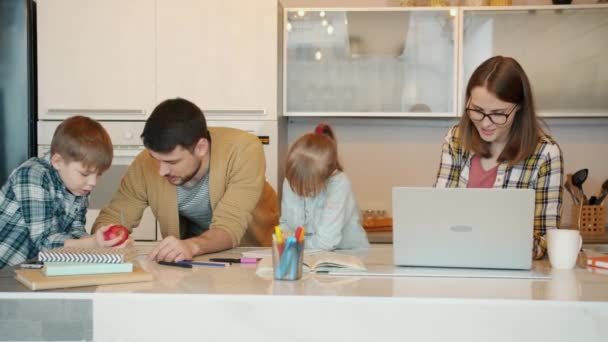 Anne ve babayı sevmek, ev ödevi yapan kadınlara evde dizüstü bilgisayar kullanarak yardım etmek. — Stok video