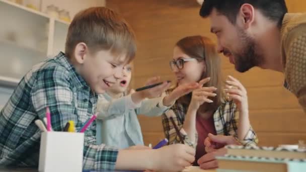 Snabb rörelse av lycklig familj pratar och gester upptagen med barnens läxor inomhus — Stockvideo