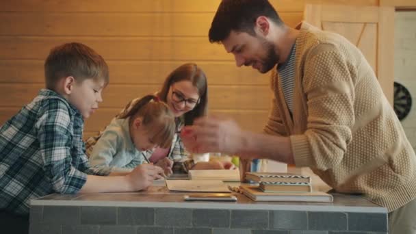 Movimento lento de pais inteligentes ajudando crianças menino e menina com lição de casa em casa — Vídeo de Stock