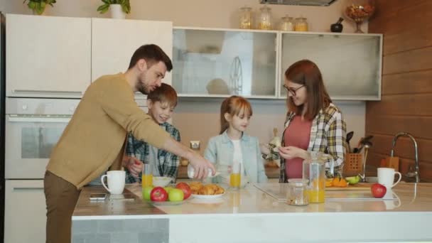 Pais amorosos fazendo café da manhã para crianças conversando e expressando amor na cozinha em casa — Vídeo de Stock
