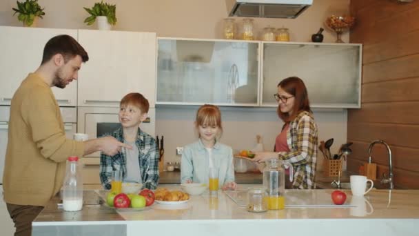 Långsam rörelse av lycklig familj gravid mor far son och dotter pratar äta frukost i köket — Stockvideo