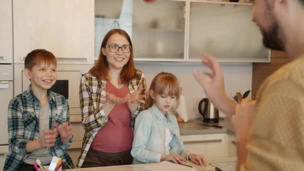 Zpomalený pohyb táta hraje se synem házení jablka, zatímco žena a dívka dělá domácí úkoly v kuchyni doma — Stock video