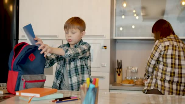 Mama daje pudełko na lunch dla dzieci całujących się przytulając, podczas gdy syn szykuje się do szkoły — Wideo stockowe