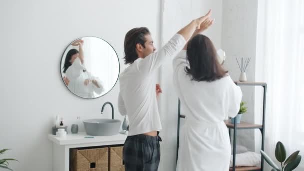 Slow motion van gelukkig paar man en vrouw dansen in de badkamer hand in hand — Stockvideo