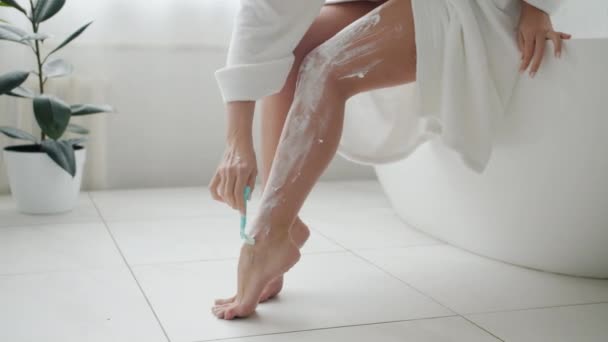 Close-up van vrouwelijke benen bedekt met scheerschuim en handmatig verwijderen van haar met scheermes — Stockvideo