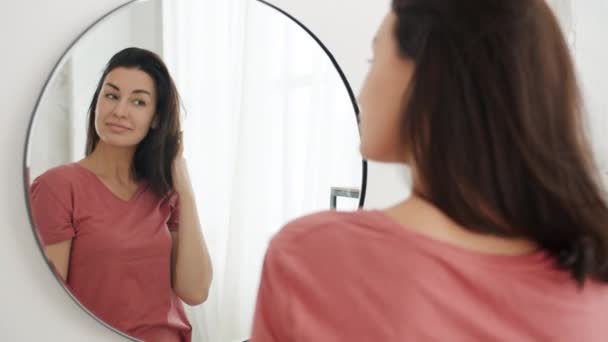 Portret van aantrekkelijk meisje op zoek naar spiegel in de badkamer aanraken van haar glimlachen — Stockvideo