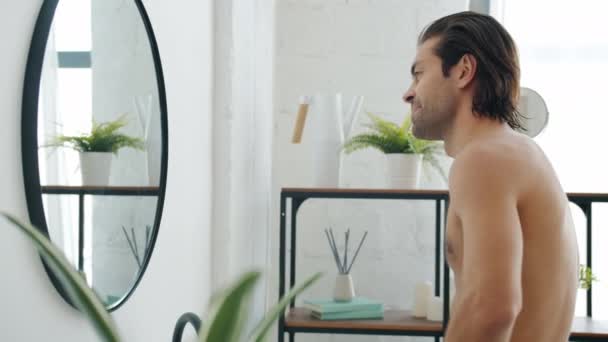 Slow motion van goed uitziende jonge man poseren kijken spiegel reflectie in de badkamer — Stockvideo