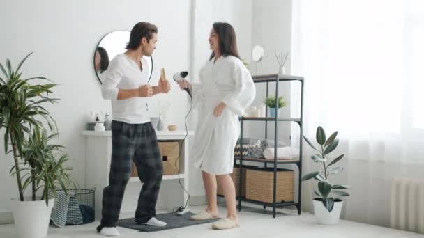 Cámara lenta de alegre novio y novia cantando y bailando disfrutando de la música en el baño — Vídeos de Stock