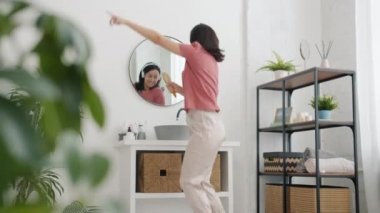 Pijamalı, banyoda dans eden ve kulaklık takan aktif kadının hızlı hareketi.