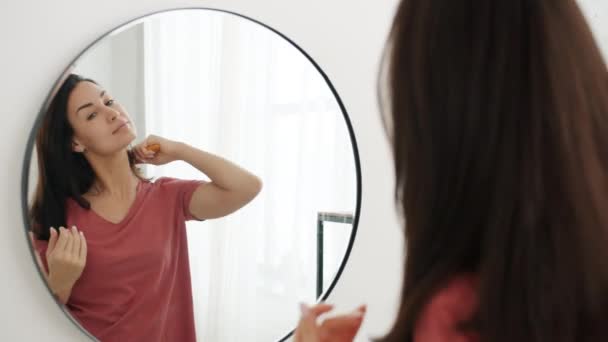 Movimiento lento de la mujer atractiva cepillarse el cabello mirando el espejo en el baño — Vídeos de Stock